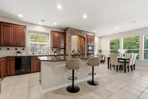a kitchen with stainless steel appliances granite countertop a stove a sink a dining table and chairs