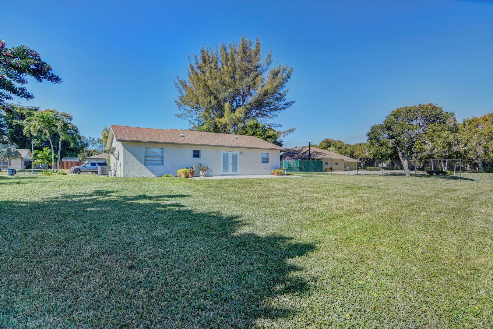 9989 Liberty Road Boca Raton, FL 33434 - Photo 24 of 44 a front view of house with yard and trees