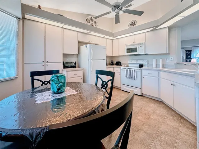 a kitchen with kitchen island granite countertop a table chairs sink and cabinets