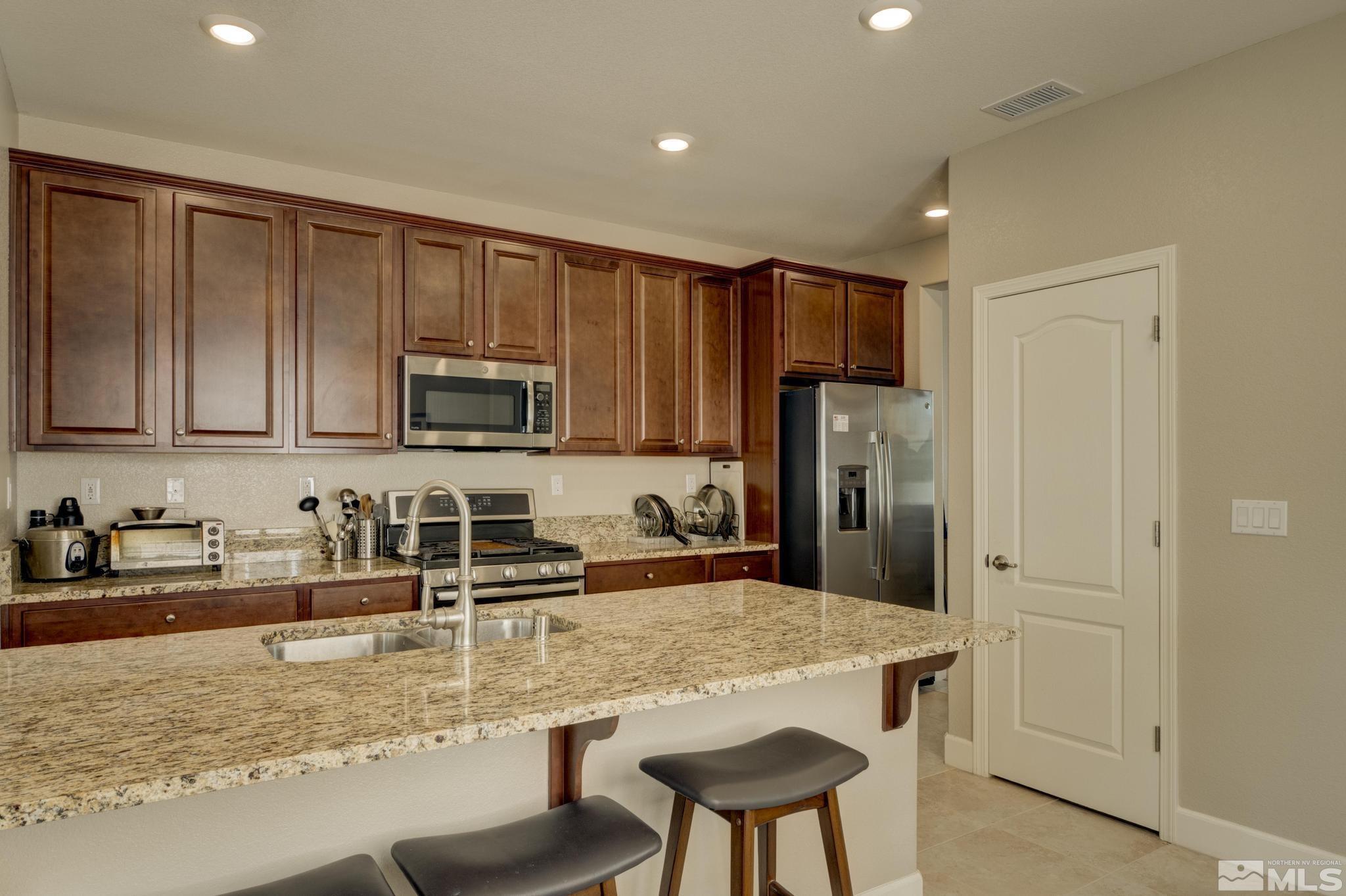 10180 Culiacan Pass Trail Reno, NV 89521 - Photo 7 of 34 a kitchen with stainless steel appliances granite countertop a refrigerator a stove a sink a dining table and chairs