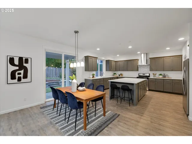 a open kitchen with stainless steel appliances kitchen island granite countertop a table chairs and a refrigerator