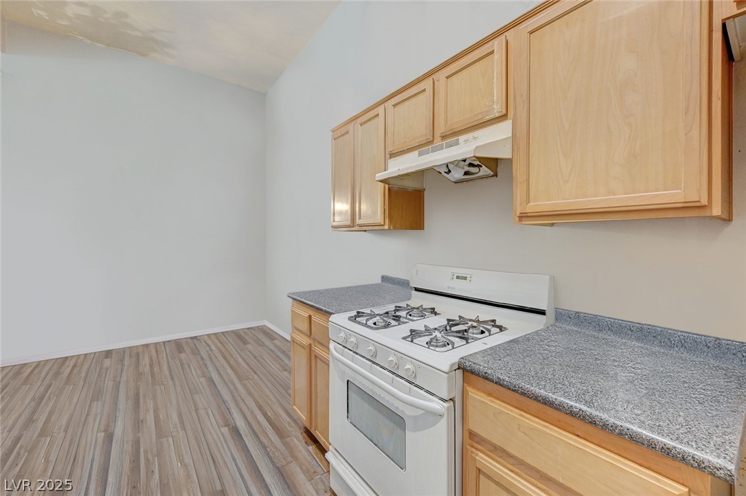 2305 West Horizon Ridge Parkway, Unit 1223 Henderson, NV 89052 - Photo 14 of 28 Kitchen with white gas range oven, light wood finish cabinets, light wood-type flooring, and dark countertops