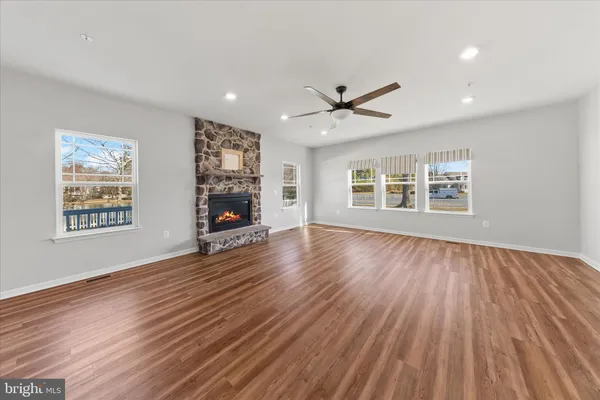 a kitchen with stainless steel appliances granite countertop a refrigerator a sink dishwasher a stove and white countertops with wooden floor