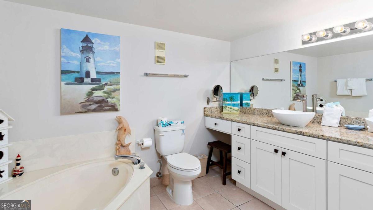 1440 Ocean Boulevard, Unit 224 St. Simons, GA 31522 - Photo 11 of 26 a bathroom with a granite countertop sink mirror vanity and toilet