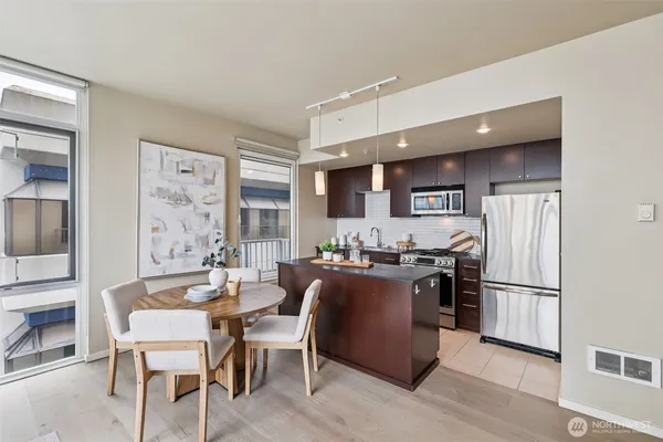 a kitchen with stainless steel appliances granite countertop a refrigerator a stove a sink dishwasher and a dining table with wooden floor