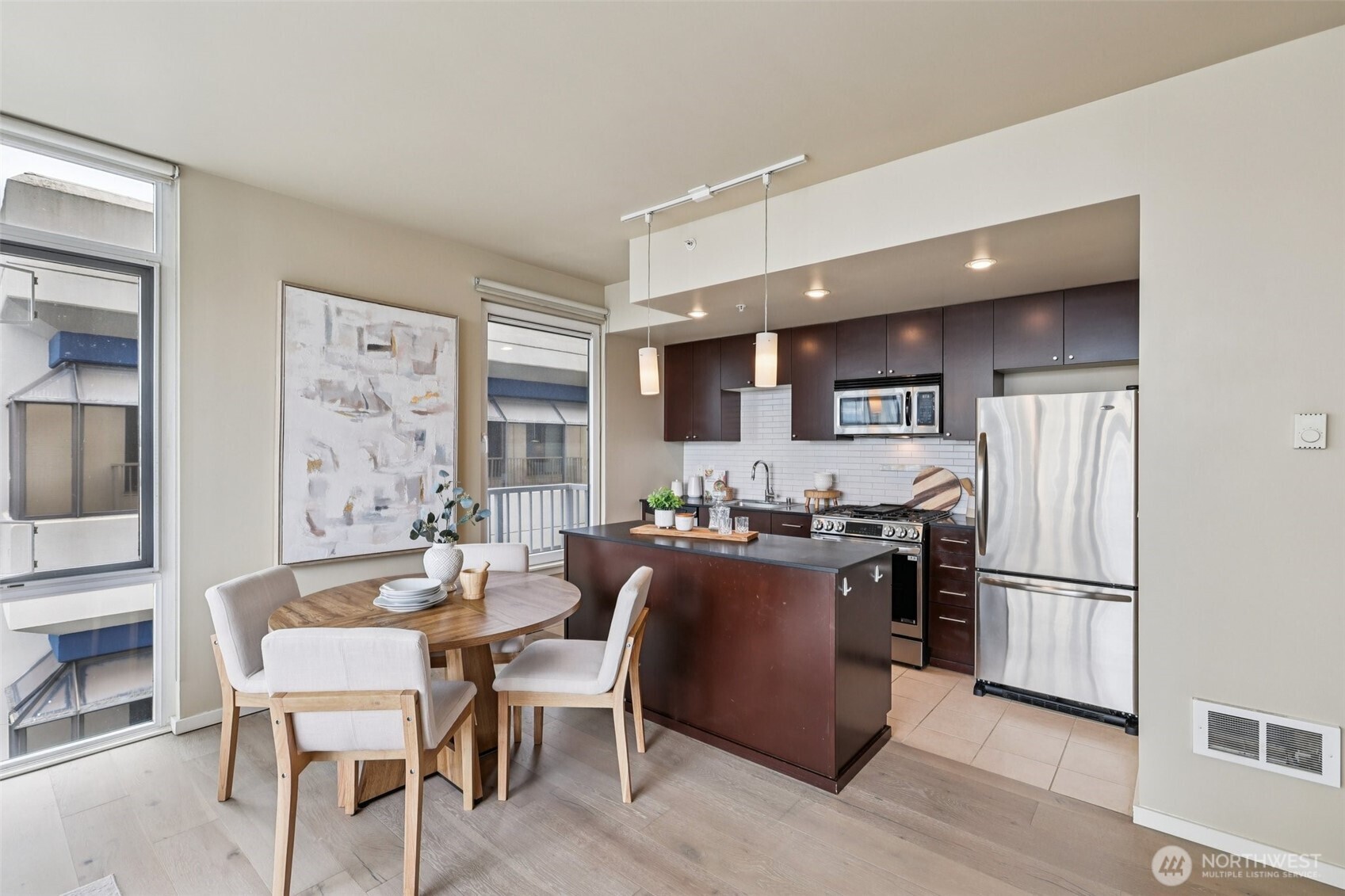 76 Cedar Street, Unit S1005 Seattle, WA 98121 - Photo 5 of 30 a kitchen with stainless steel appliances granite countertop a refrigerator a stove a sink dishwasher and a dining table with wooden floor