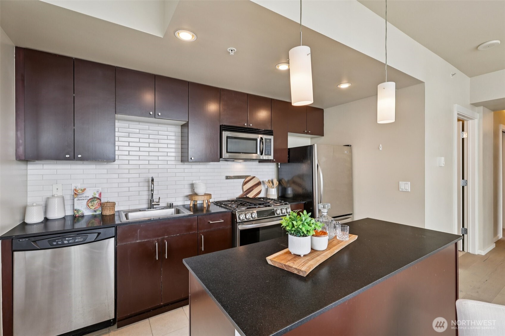 76 Cedar Street, Unit S1005 Seattle, WA 98121 - Photo 7 of 30 a kitchen with stainless steel appliances granite countertop a refrigerator a sink dishwasher a stove and a dining table with wooden floor