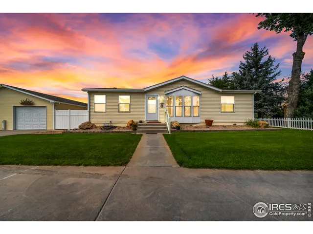 a view of house in front of a big yard with large trees