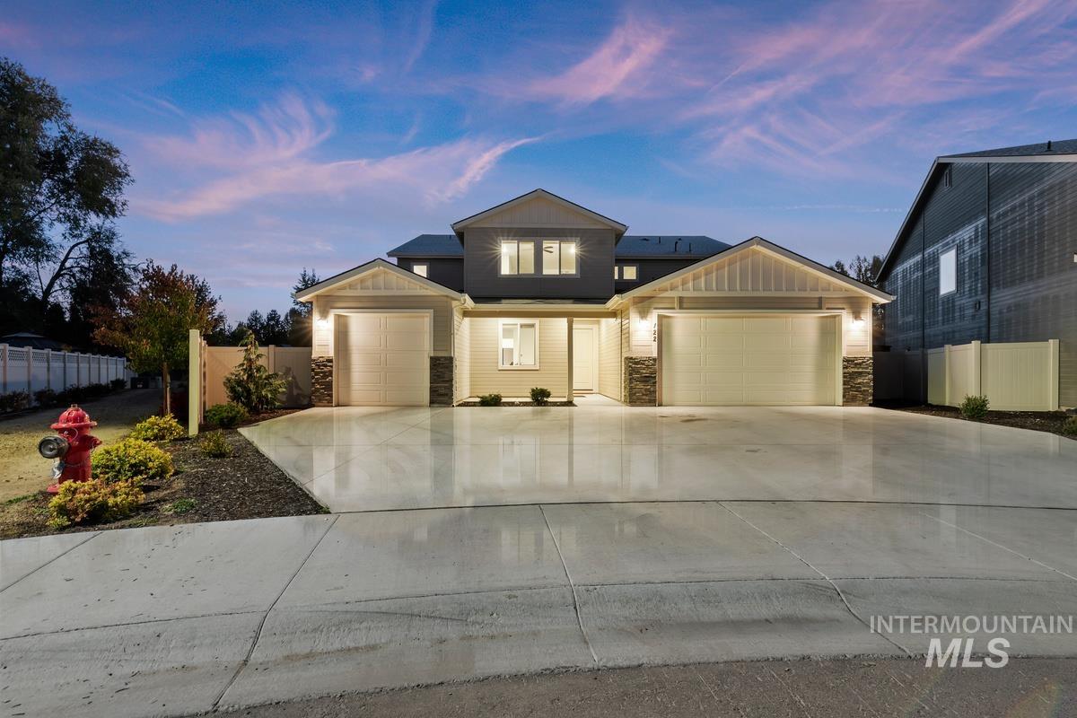 View of front of property featuring stone siding, board and batten siding, an attached garage, and driveway