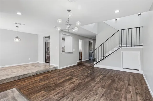 wooden floor in an empty room with a chandelier fan