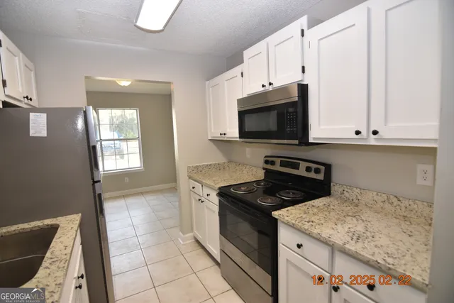 a kitchen with granite countertop a stove sink and microwave