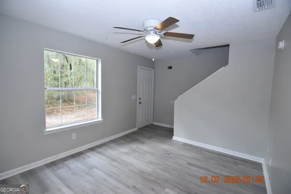 a view of an empty room with wooden floor and a window