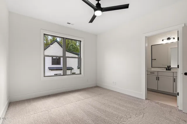 an empty room with ceiling fan and windows