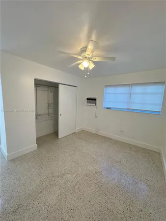 an empty room with a ceiling fan and a window