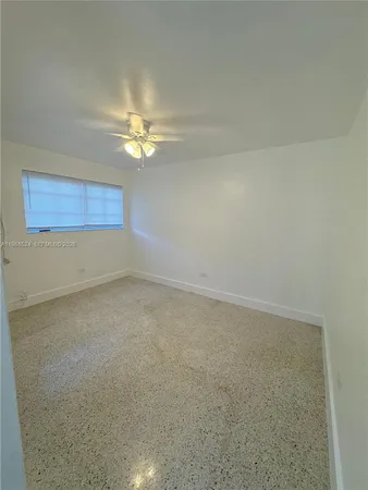 an empty room with a chandelier fan and windows