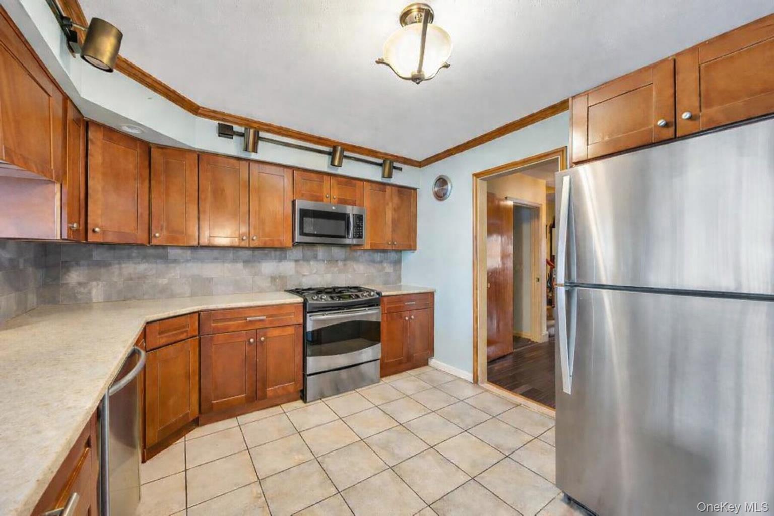 7 North Terrace Place Valley Stream, NY 11580 - Photo 14 of 40 a kitchen with stainless steel appliances granite countertop a refrigerator a stove top oven a sink and dishwasher