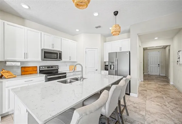 a kitchen with stainless steel appliances granite countertop a sink a stove a refrigerator a microwave oven with white cabinets