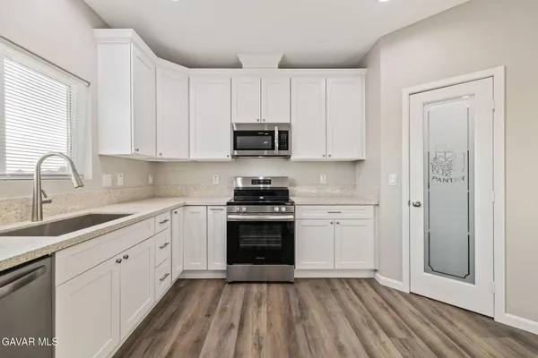 a large white kitchen with granite countertop a sink and dishwasher a refrigerator with white cabinets