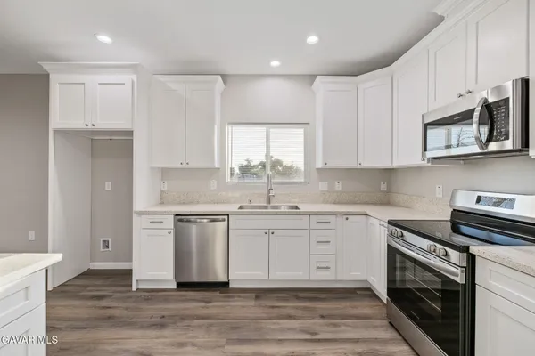 a kitchen with granite countertop a stove top oven and cabinets