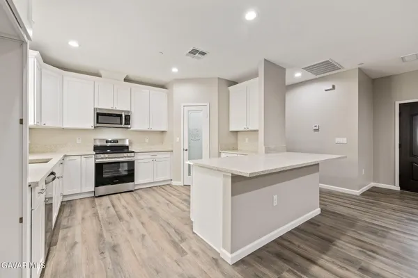 a view of a kitchen with white cabinets and wooden floor