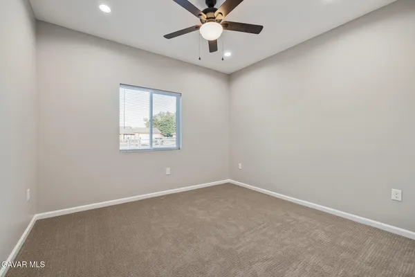an empty room with a ceiling fan and window