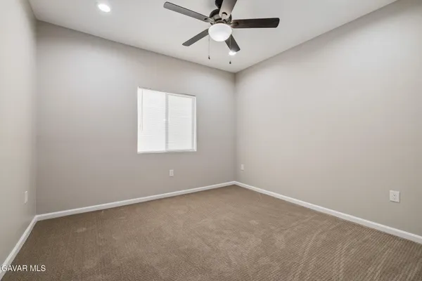 an empty room with a ceiling fan and a window