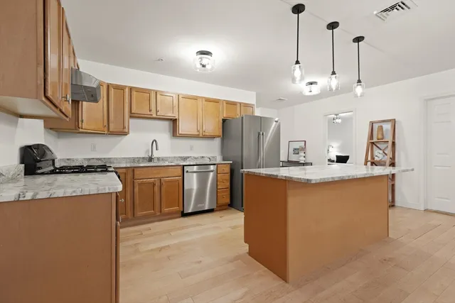 a kitchen with stainless steel appliances granite countertop a sink a stove and a refrigerator