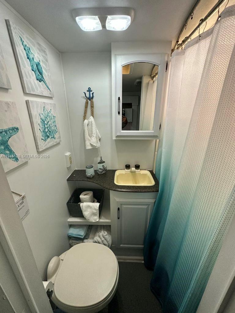 325 Calusa, Unit 9 Key Largo, FL 33037 - Photo 9 of 11 a bathroom with a toilet a sink and a mirror