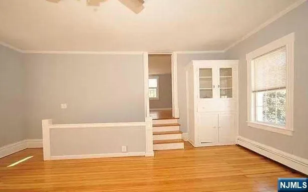 a view of empty room with wooden floor and fan