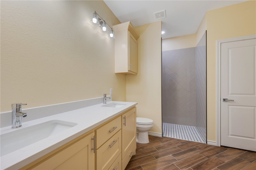 1108 Richard Street, Unit A Bryan, TX 77803 - Photo 18 of 22 Bathroom with a tile shower, double vanity, and wood tiled floors