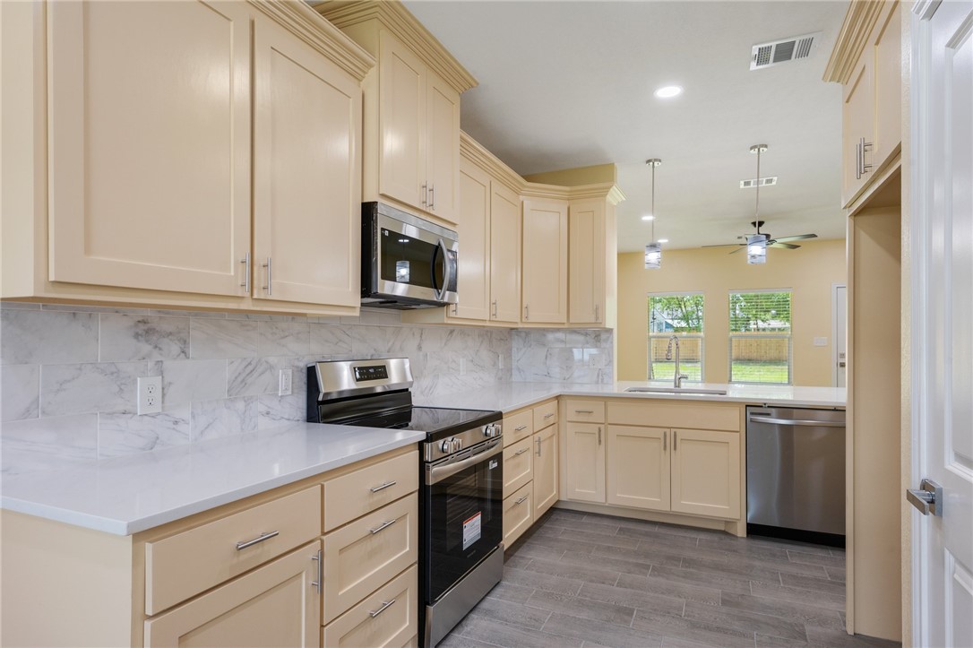 1108 Richard Street, Unit A Bryan, TX 77803 - Photo 2 of 22 Kitchen featuring stainless steel appliances, cream cabinets, a ceiling fan, decorative backsplash, and light countertops
