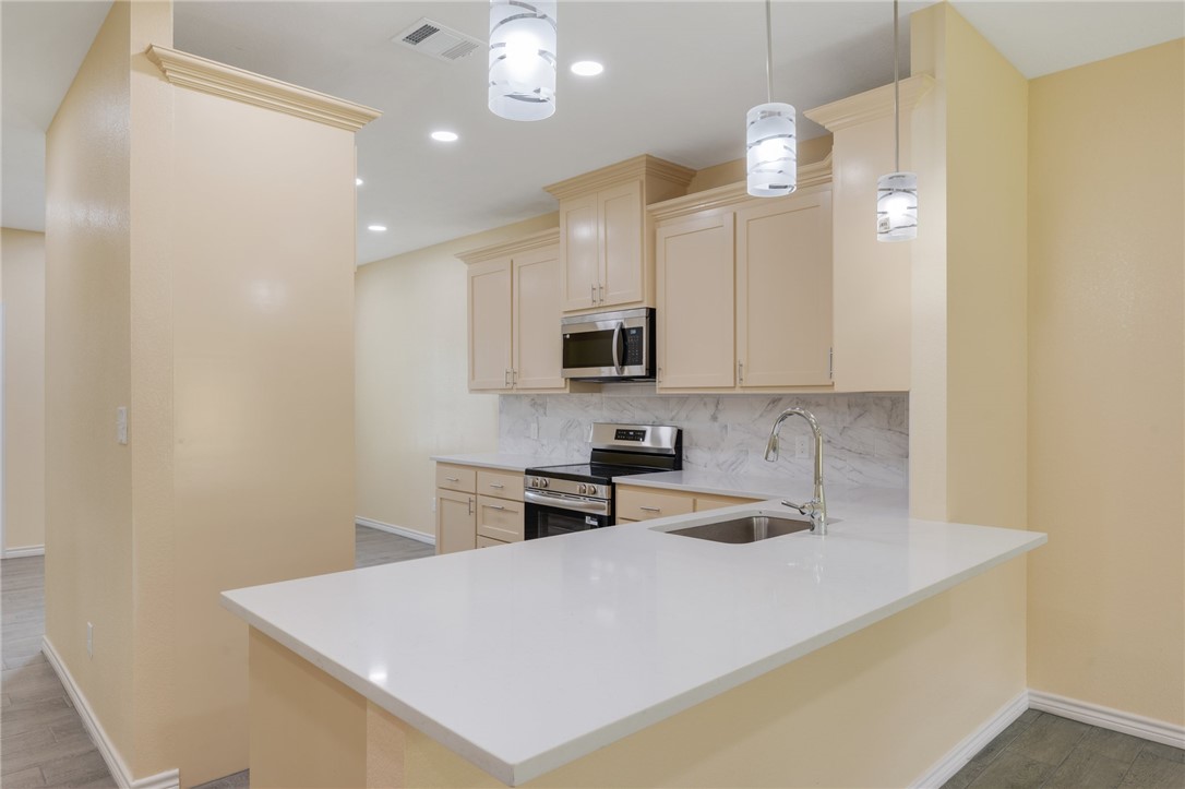 1108 Richard Street, Unit A Bryan, TX 77803 - Photo 3 of 22 Kitchen featuring appliances with stainless steel finishes, tasteful backsplash, light countertops, cream cabinets, and a peninsula