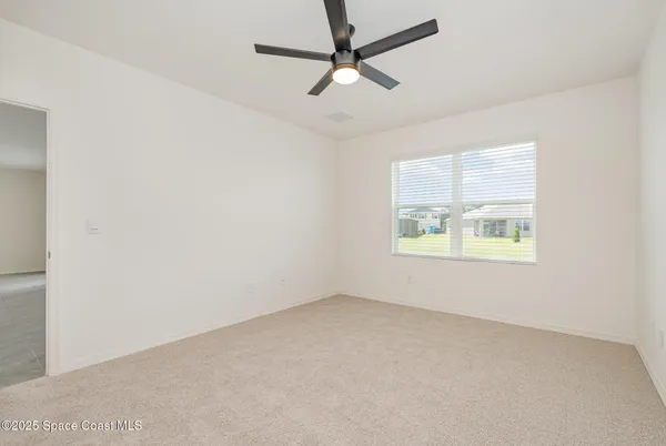 an empty room with a window and a ceiling fan