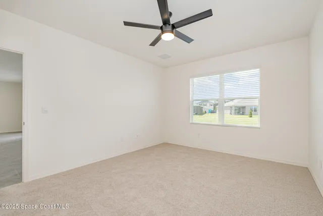 an empty room with a window and a ceiling fan