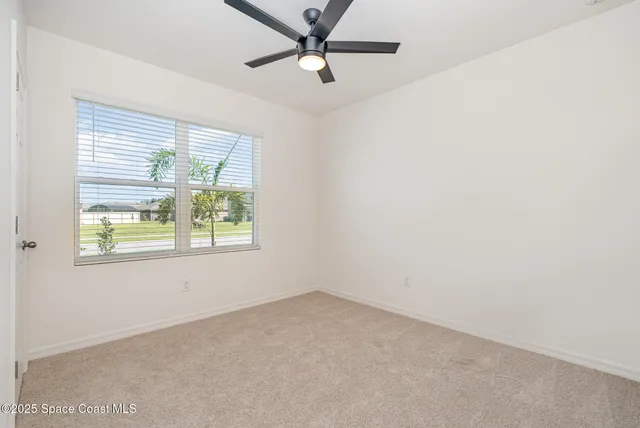 an empty room with a window and a ceiling fan