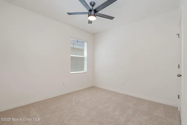 an empty room with a window and ceiling fan