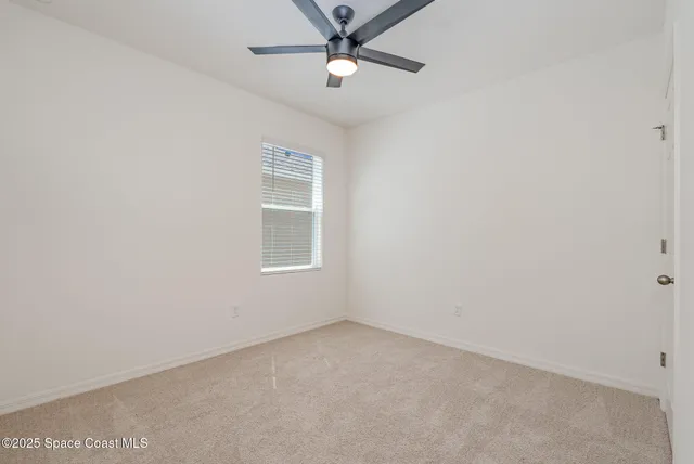 an empty room with a window and ceiling fan