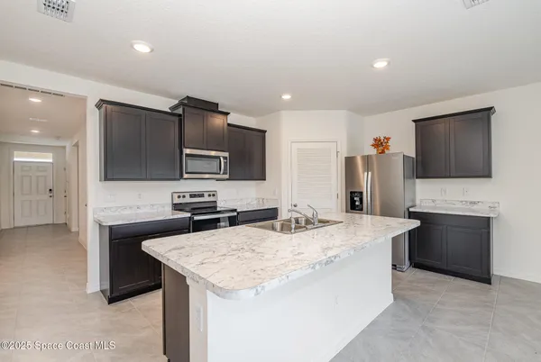 a kitchen with stainless steel appliances kitchen island granite countertop a stove top oven a sink and a refrigerator