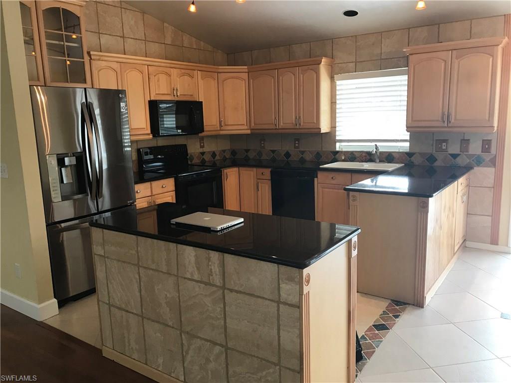 9108 Henry Road Fort Myers, FL 33967 - Photo 2 of 18 a kitchen with granite countertop a refrigerator and a sink