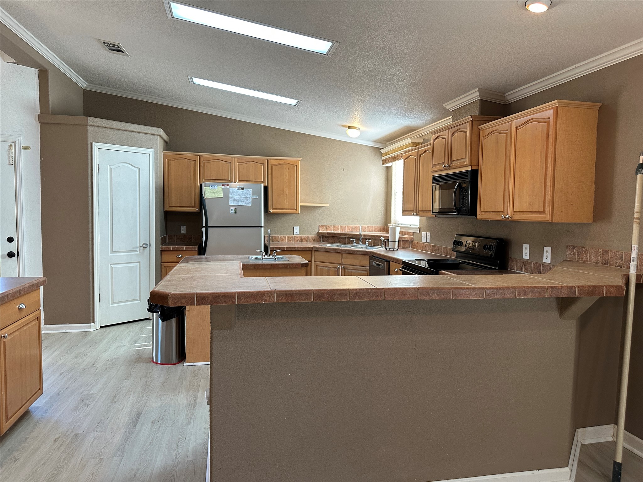 438 Mt Olive Road, Unit A Cedar Creek, TX 78612 - Photo 5 of 27 Kitchen with a kitchen breakfast bar, light wood finish cabinets, black & stainless steel appliances.
Open to the living room.