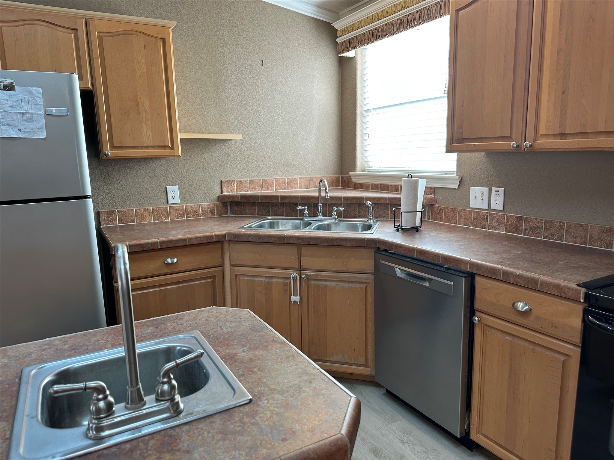 438 Mt Olive Road, Unit A Cedar Creek, TX 78612 - Photo 8 of 27 Kitchen featuring a textured wall, stainless steel appliances, dark countertops, ornamental molding, and light wood-style flooring