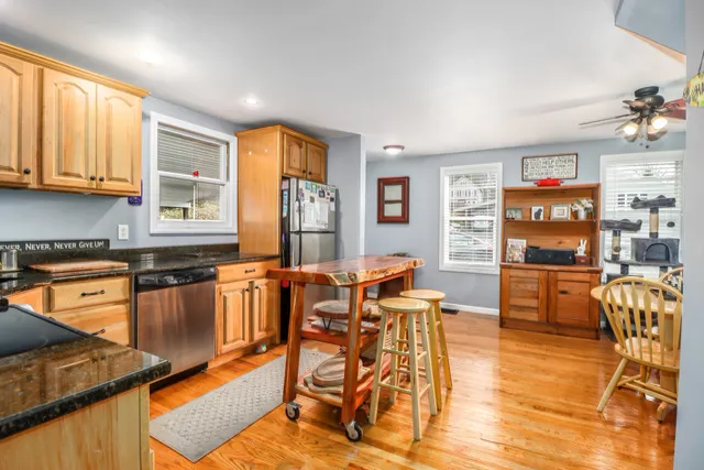 a kitchen with stainless steel appliances granite countertop a stove top oven a dining table and chairs with wooden floor