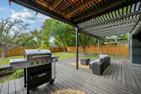 a view of a patio with couches table and chairs with wooden floor and fence next to a yard