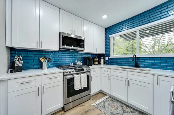 a kitchen with white cabinets sink and appliances