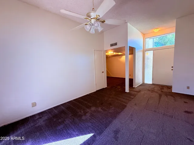 a view of an empty room with window chandelier fan