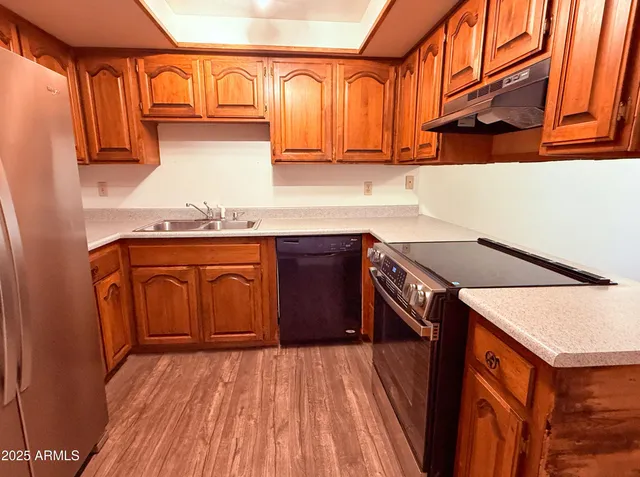 a kitchen with a sink a stove top oven and cabinetry