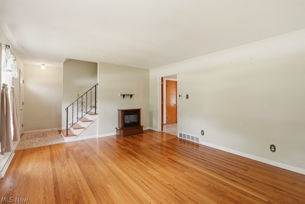 161 Pinehurst Road Munroe Falls, OH 44262 - Photo 6 of 40 Spacious living area featuring polished wood-finish flooring, a built-in fireplace with a wood-finish surround, and a staircase with a black wrought iron railing