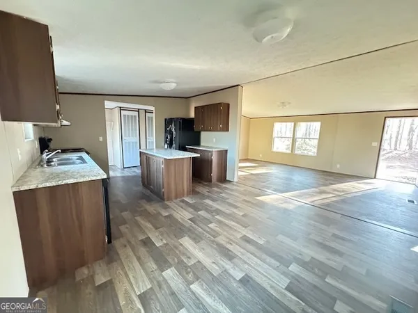 a living room with stainless steel appliances furniture a flat screen tv and kitchen view