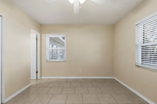 a view of an empty room with window and chandelier fan