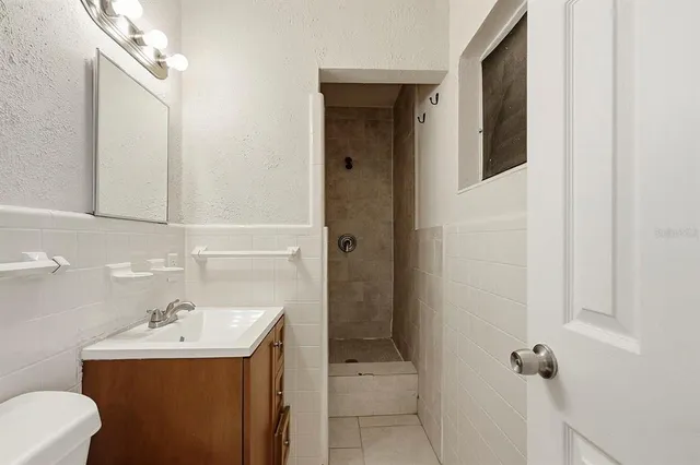 a view of an empty room with window and chandelier fan